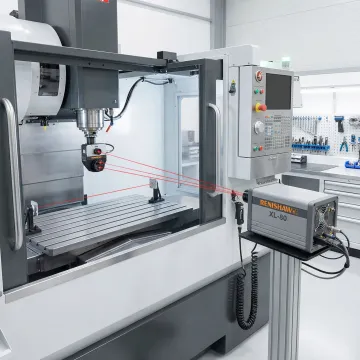 CNC machining center undergoing precision calibration with laser interferometer equipment
