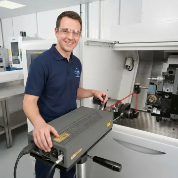 Technician performing laser interferometer calibration on CNC machine
