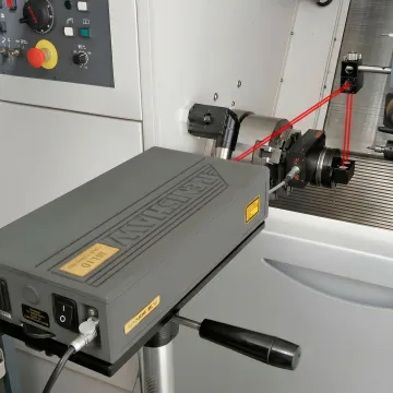 Close-up of precision laser measurement equipment calibrating CNC machine axis