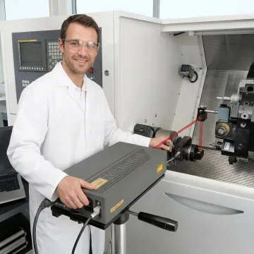 CNC machine calibration technician performing laser interferometer measurement on precision manufacturing equipment