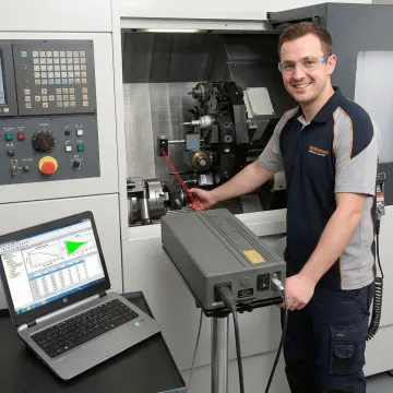 Technician performing precision machine calibration inspection on CNC equipment