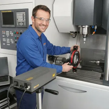 Technician performing ballbar testing on CNC machine with wireless measurement system