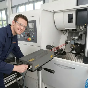 Technician performing laser calibration measurement on CNC milling machine