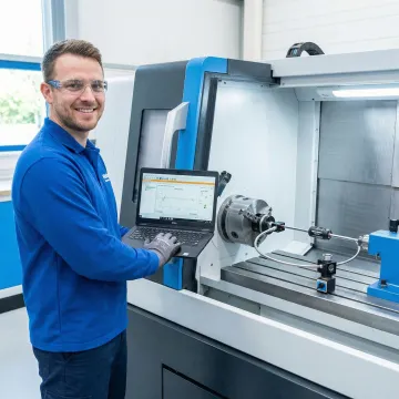 Technician performing CNC ballbar testing on a precision milling machine