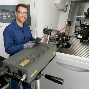 CNC machine calibration technician performing laser interferometer testing on precision milling equipment