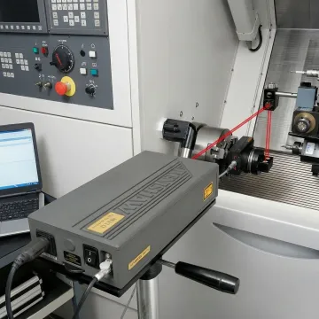 Precision laser measurement system calibrating CNC machine in manufacturing facility