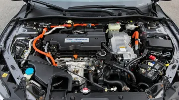 Electric vehicle engine bay with high-voltage warning labels and orange wiring harness