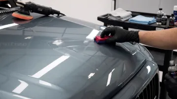Professional detailer applying ceramic coating to luxury car exterior