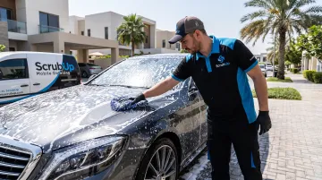 Mobile car detailing technician performing gentle foam wash on vehicle