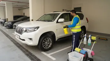 Mobile car wash technician cleaning vehicle in Dubai basement parking
