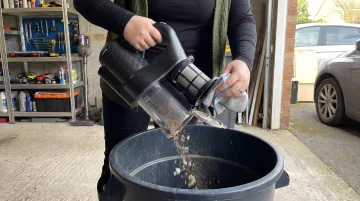Person emptying car vacuum canister and cleaning filter after use