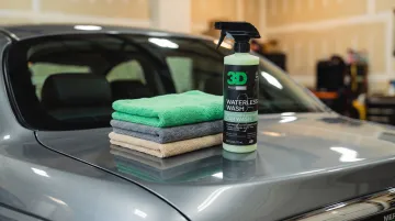 Waterless car wash spray bottle and microfiber towels on car hood