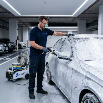 Technician washing a car in a Dubai parking area