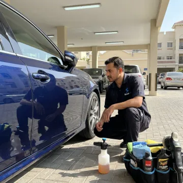 Technician inspecting polished car paint