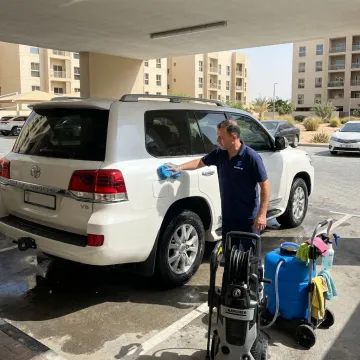 Mobile car wash technician cleaning a car in Dubai parking