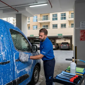 Mobile car wash technician cleaning a car in Dubai