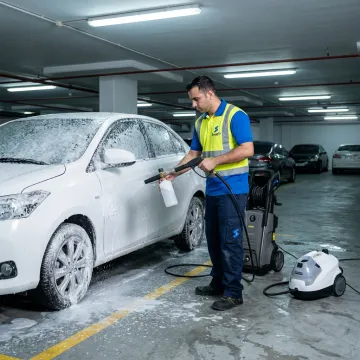 Mobile car wash technician cleaning a car in Dubai parking