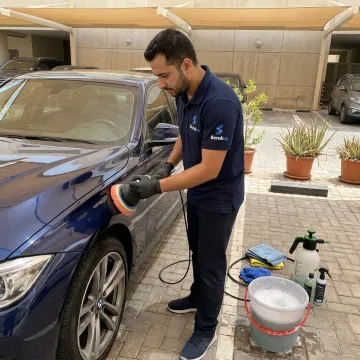 Technician detailing a BMW in Dubai parking