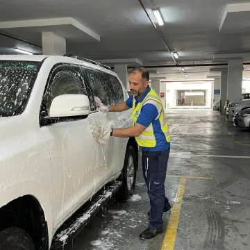 Mobile car wash technician cleaning a parked vehicle