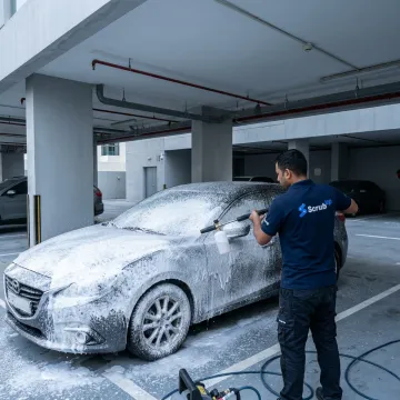 Mobile technician applying snow foam to a car
