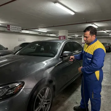 Mobile car wash technician cleaning a car in Dubai parking