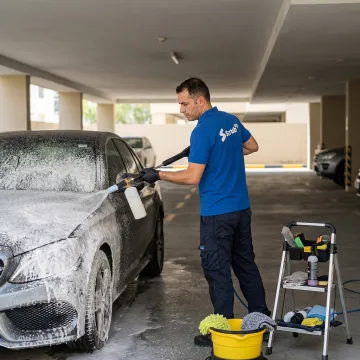 Mobile car wash technician cleaning a car in Dubai parking