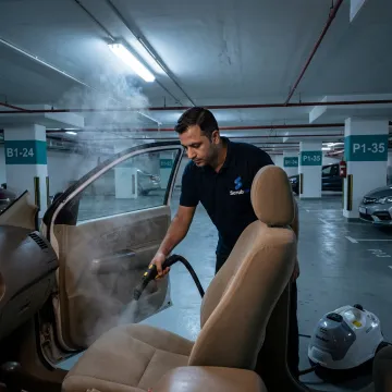 Mobile technician steam cleaning a car interior