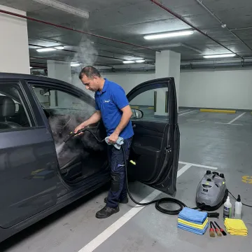 Technician steam cleaning a car interior