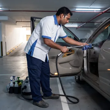 Technician steam cleaning a car interior