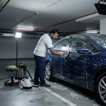 Mobile car wash technician cleaning vehicle in Dubai parking area