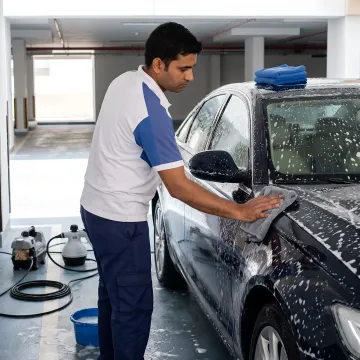Mobile car detailer cleaning a parked vehicle