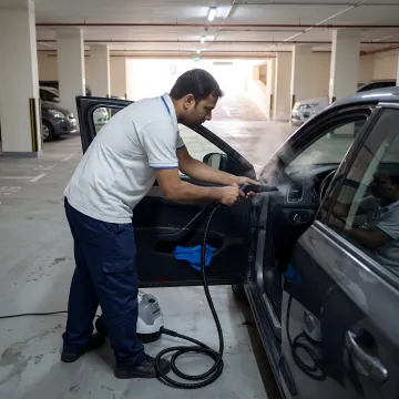 Technician steam cleaning car interior