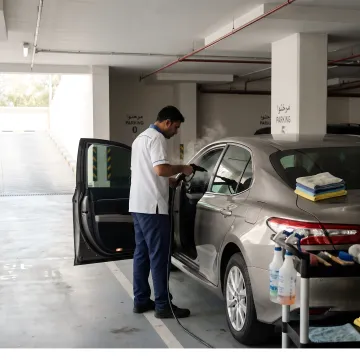 Mobile detailer cleaning a car in a parking bay