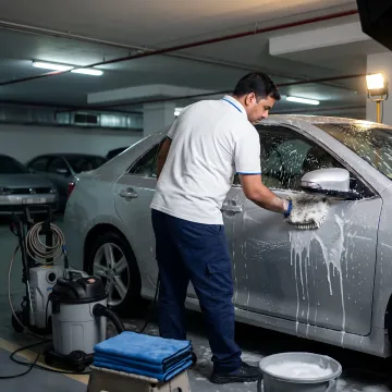 Mobile technician washing car in parking area