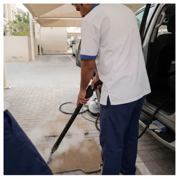 Technician steam cleaning car floor mats