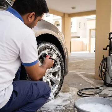 Technician cleaning car wheel and tyre