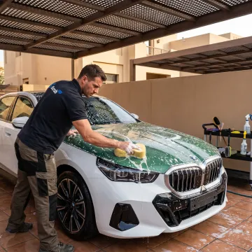 Technician washing a car at a Dubai residential parking space