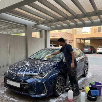 Mobile technician washing a car in Dubai parking