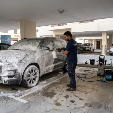 Technician applying foam to a parked car