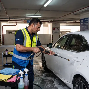 Technician washing a car in a Dubai parking space