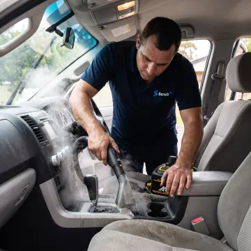 Mobile technician steam-cleaning a car interior