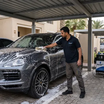 Technician washing a car at a residential parking spot