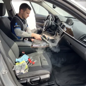 Technician steam-cleaning a car interior
