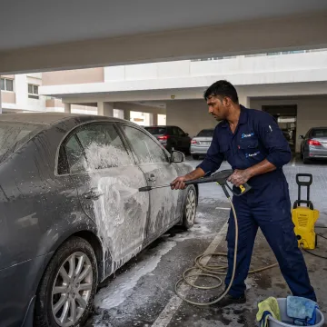 Technician pressure washing a car at a Dubai parking space