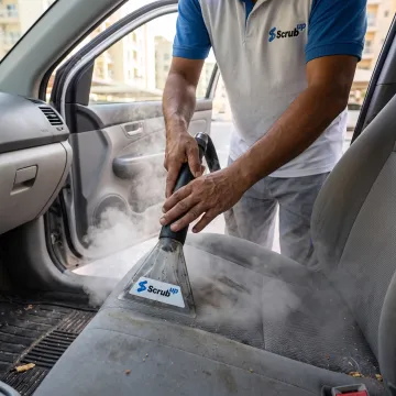 Mobile technician steam-cleaning a car interior
