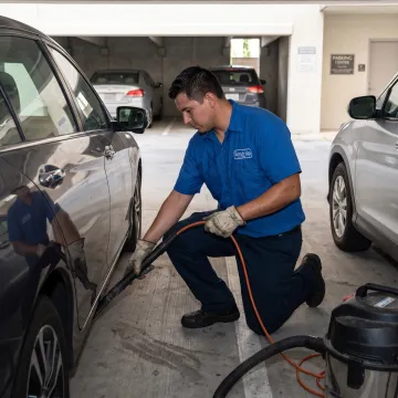 Technician detailing a vehicle at a customer parking spot