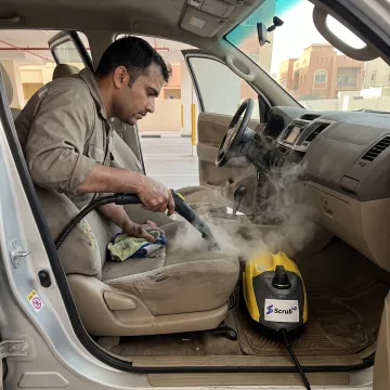Technician steam-cleaning a vehicle interior