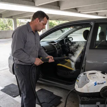 Technician steam-cleaning a car interior
