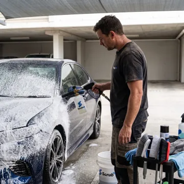 Technician washing a car at a parking space