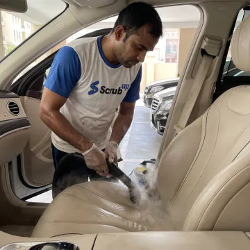 Technician steam-cleaning a car interior
